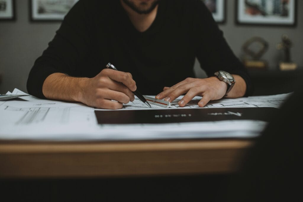 Freelancer at a desk holding their forehead while looking at a phone and laptop screen