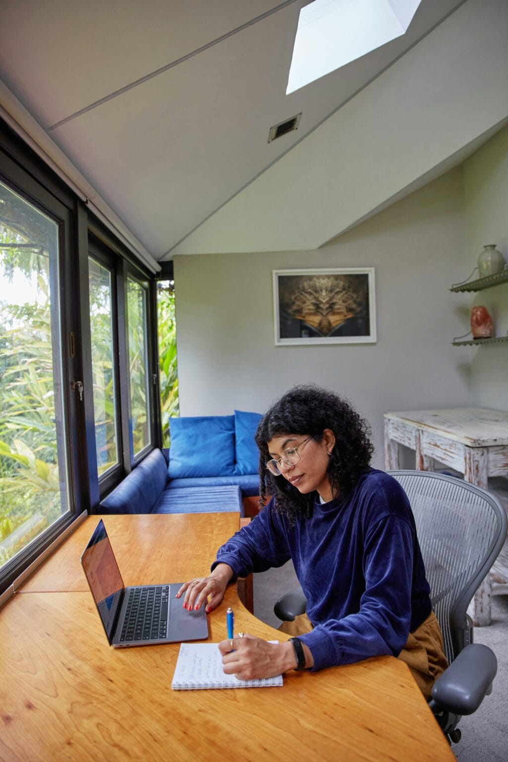 Freelancer at a kitchen table with laptop, paper receipts, and a coffee mug