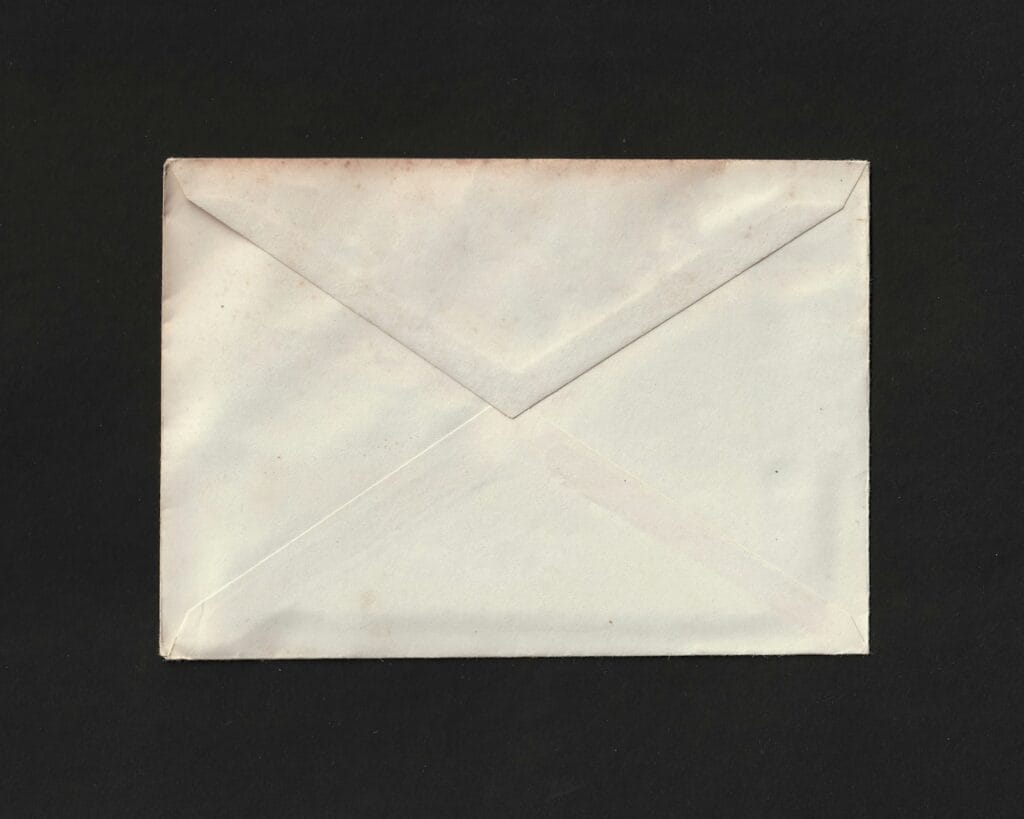 Person at a home desk opening a tax form envelope in evening light