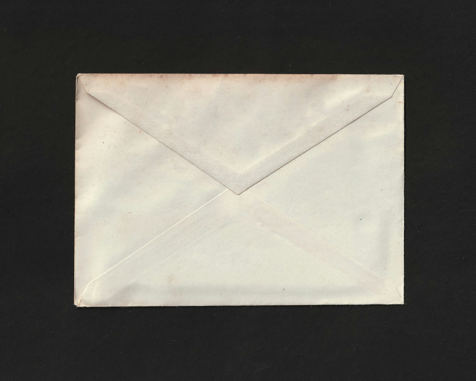 Person at a home desk opening a tax form envelope in evening light